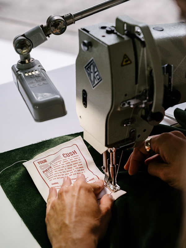 Close-up of a Culture Cush label being stitched onto fabric in Newcastle, highlighting handmade custom modular lounge craftsmanship.
