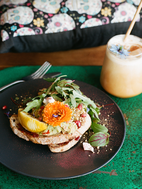 Colourful brunch dish with avocado toast, edible flowers, and juice at Lords of Pour café in Ettalong.
