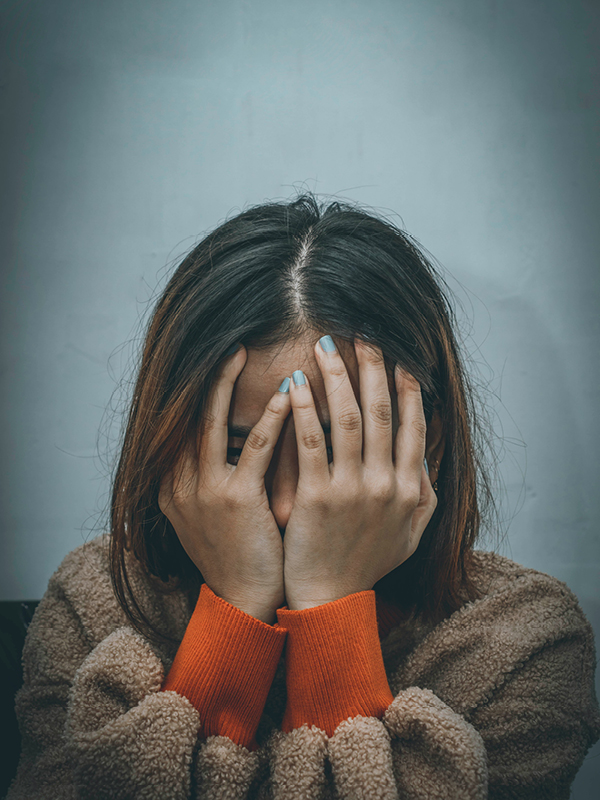 Woman with hands covering her face, expressing sadness and overwhelm – photo by Dev Asangbam.