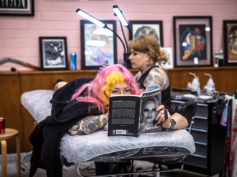 Client reading a book while getting tattooed at FLT Tattoo Studio in Newcastle, reflecting the studio’s calm, comfortable and inclusive atmosphere.