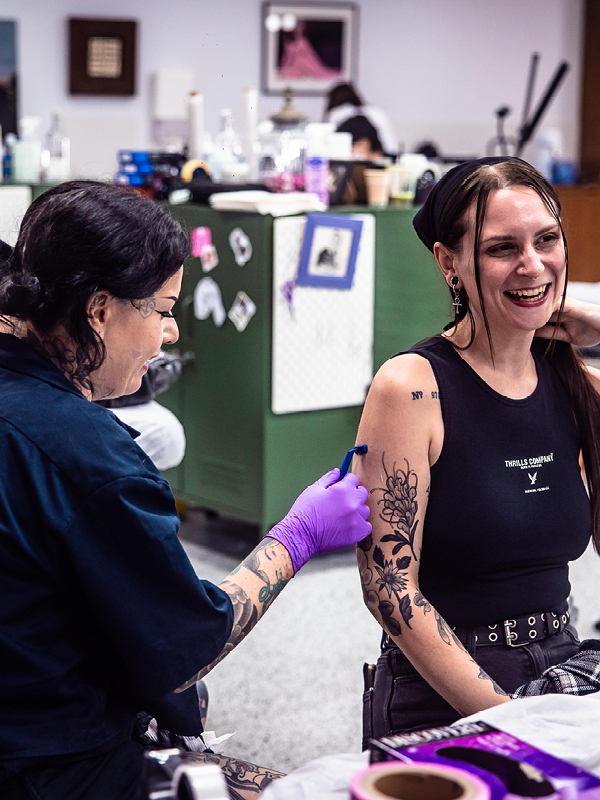 Tattoo artist at FLT Tattoo Studio in Newcastle working with a smiling client during a tattoo session, showcasing the studio’s warm and inclusive atmosphere.