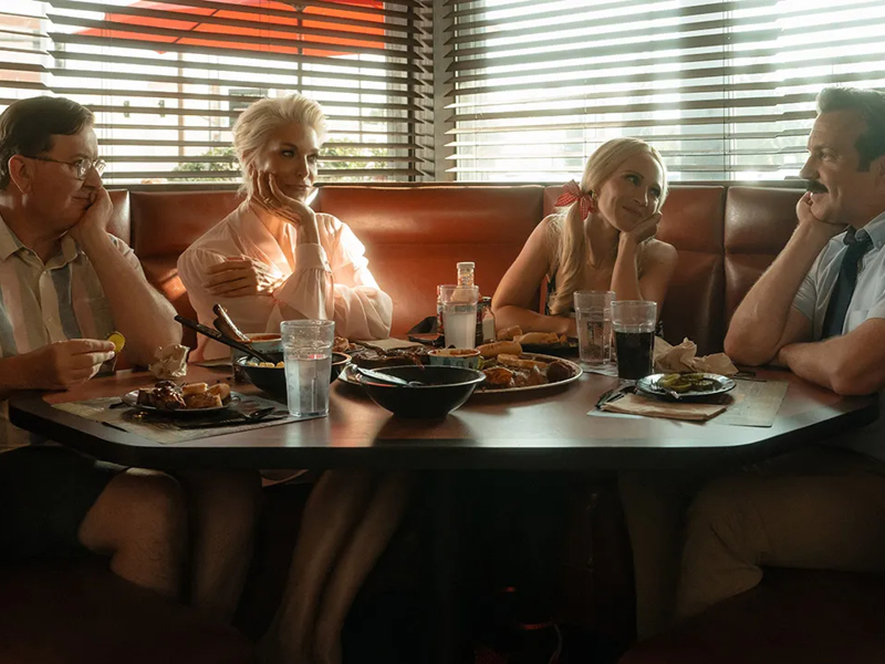 Jason Sudeikis as Ted Lasso with cast members in a diner scene from season 4.