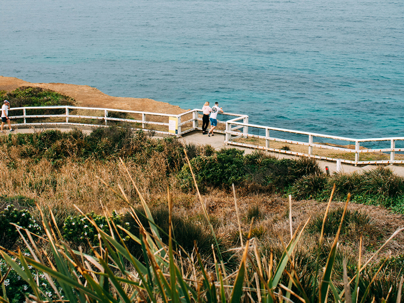 People walking along the coastal path at Merewether, overlooking the ocean and surrounding dune vegetation.