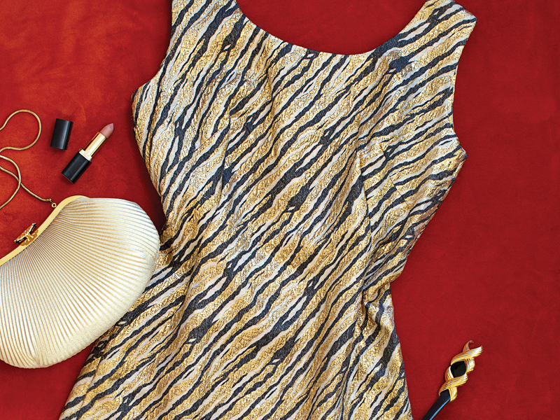 Gold and black patterned vintage dress styled with a clutch and lipstick from The Retro Wardrobe in Newcastle.