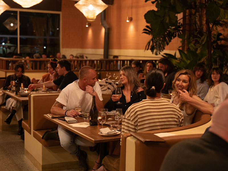 Guests enjoying dinner and drinks at Papalote Mexican restaurant in Newcastle, surrounded by warm lighting and lush greenery.