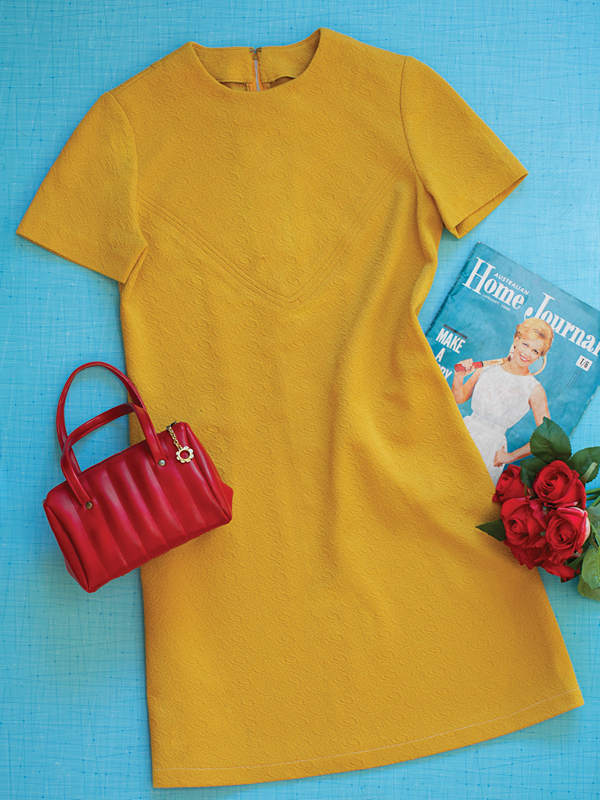 Mustard-yellow vintage shift dress with red handbag and roses from The Retro Wardrobe Newcastle.